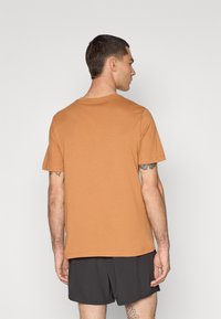 Korte ermer, rund hals t-skjorte i varm oransje, laget av mykt stoff. Har en avslappet passform og enkel design uten synlige logoer eller mønstre.
