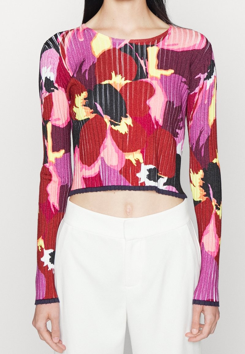 Hedvábný pletený crop top v živých květinových vzorech v odstínech červené, růžové a žluté. Má dlouhé rukávy a kontrastní lem.
