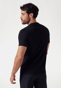 Zwarte t-shirt met korte mouwen en een ronde halslijn, gemaakt van zachte stof. Fittend model met minimale stiksdetails op de schouders.