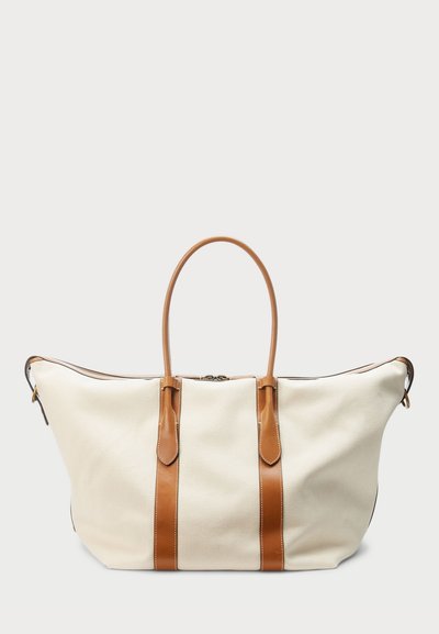 Καμβάς σακίδιο σε κρέμ χρώμα με καφέ δερμάτινες λεπτομέρειες, με δύο χερούλια, κλείσιμο με φερμουάρ και αντίθετες ραφές.