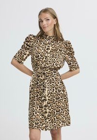 Robe en imprimé léopard avec un col, des manches bouffantes et une taille ceinturée. Fabriquée dans un tissu lisse avec une fermeture à boutons et des tons terre.