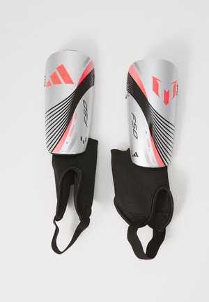 Parastinchi da calcio argento e rosa con maniche elastiche nere; presentano linee grafiche audaci e marchiatura; design leggero per la protezione.