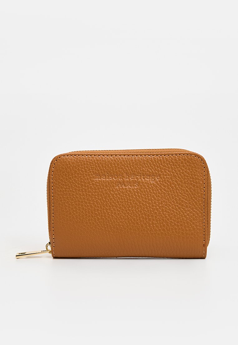 Portefeuille zippé compact en cuir tan avec une surface texturée et un logo embossé "maison heritage PARIS" à l'avant.