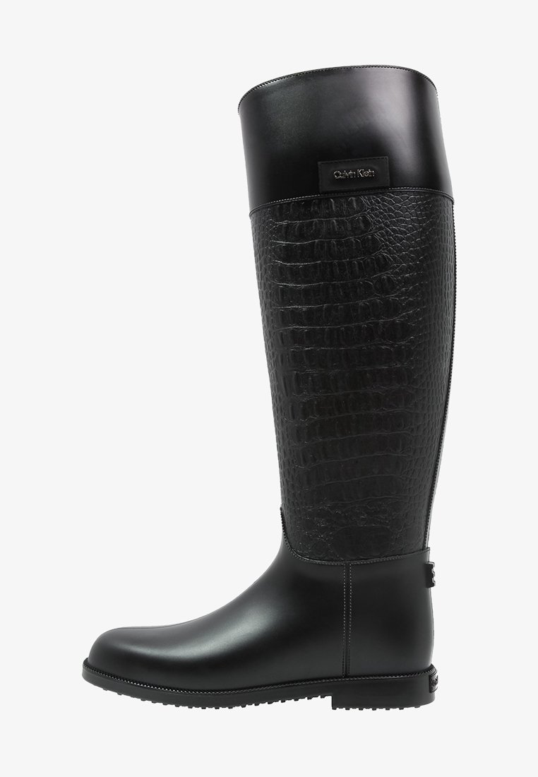 Botas de goma negras hasta la rodilla que presentan un patrón texturizado parecido a la piel de reptil en la parte superior, un acabado suave en la sección inferior y detalle del logotipo.