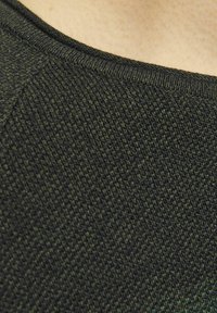 Sötétzöld, struktúrált kötött pulóver, lekerekített nyakkivágással és gondosan kidolgozott bordázott szegéllyel. Közelről készült felvétel a szövet részleteiről.