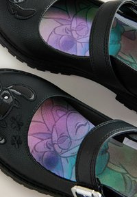 Czarne skórzane buty typu Mary Jane z okrągłym noskiem, dekoracyjnym haftem w kształcie kwiatów oraz iryzującą wkładką z kwiatowym wzorem.
