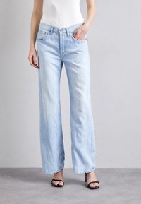 Vaaleansiniset leveälahkeiset farkut denimmateriaalista, hieman haalistuneella viimeistelyllä, joissa on kaksi etutaskua ja napillinen suljin.