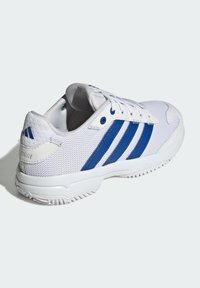 Chaussure de sport blanche avec des rayures bleues, tige en maille et semelle en caoutchouc, dotée d'une languette rembourrée et d'un système de laçage.