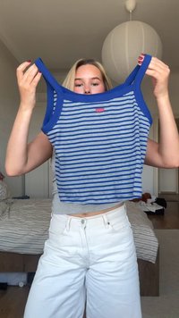 Mėlynos ir baltos juostelės nuogi marškiniai su mėlynu apvadu ir maža logotipų etikete priekyje. Medvilnin�ė medžiaga. Paprastas be rankovių dizainas.