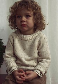 Kremno barvan pleteni pulover z debelim rebrastim ovratnikom in teksturiranim vzorcem. Dolgi rokavi z črtastimi manšetami. Mehka, udobna tkanina.