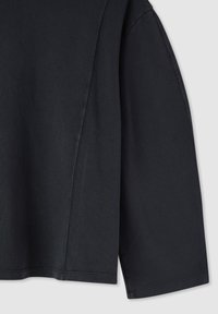 Top nero corta a maniche lunghe in morbido cotone. Presenta una vestibilità comoda con una texture liscia e dettagli cuciti lungo le cuciture.