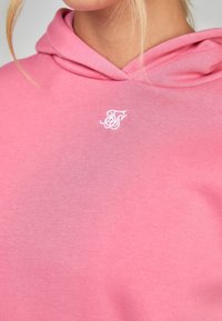 Felpa rosa realizzata in morbido cotone, con tasca frontale e un logo ricamato bianco sul petto. Cappuccio con lacci.