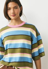 Pruhovaná košile s krátkým rukávem v modrých, zelených, žlutých, růžových a hnědých pruzích, s růžovým žebrovaným límečkem a volným střihem.