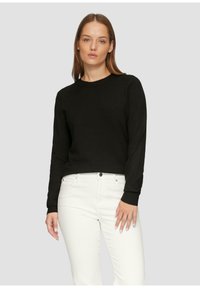 Zwart sweater met ronde hals en lange mouwen, gemaakt van een zacht materiaal, voorzien van geribde manchetten en een getailleerde snit, gedragen met witte jeans.