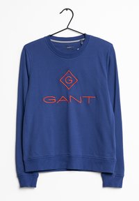 Sweat-shirt bleu avec poignets et ourlet côtelés, présentant un logo GANT orange brodé et une forme de losange sur le devant. Confectionné en tissu texturé.