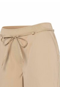 Beige Hose mit einem elastischen Bund, Kordelzug und subtiler Textur. Verfügt über Taschen und ein entspanntes Design.