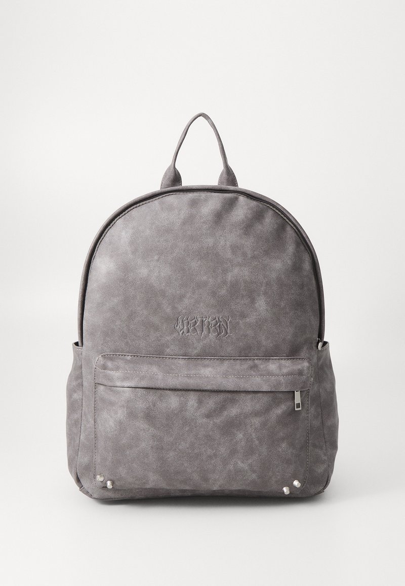 Mochila de imitación de cuero gris con forma redondeada, logotipo grabado, bolsillo frontal con cremallera y detalles en metal plateado. Acabado suave y texturizado.