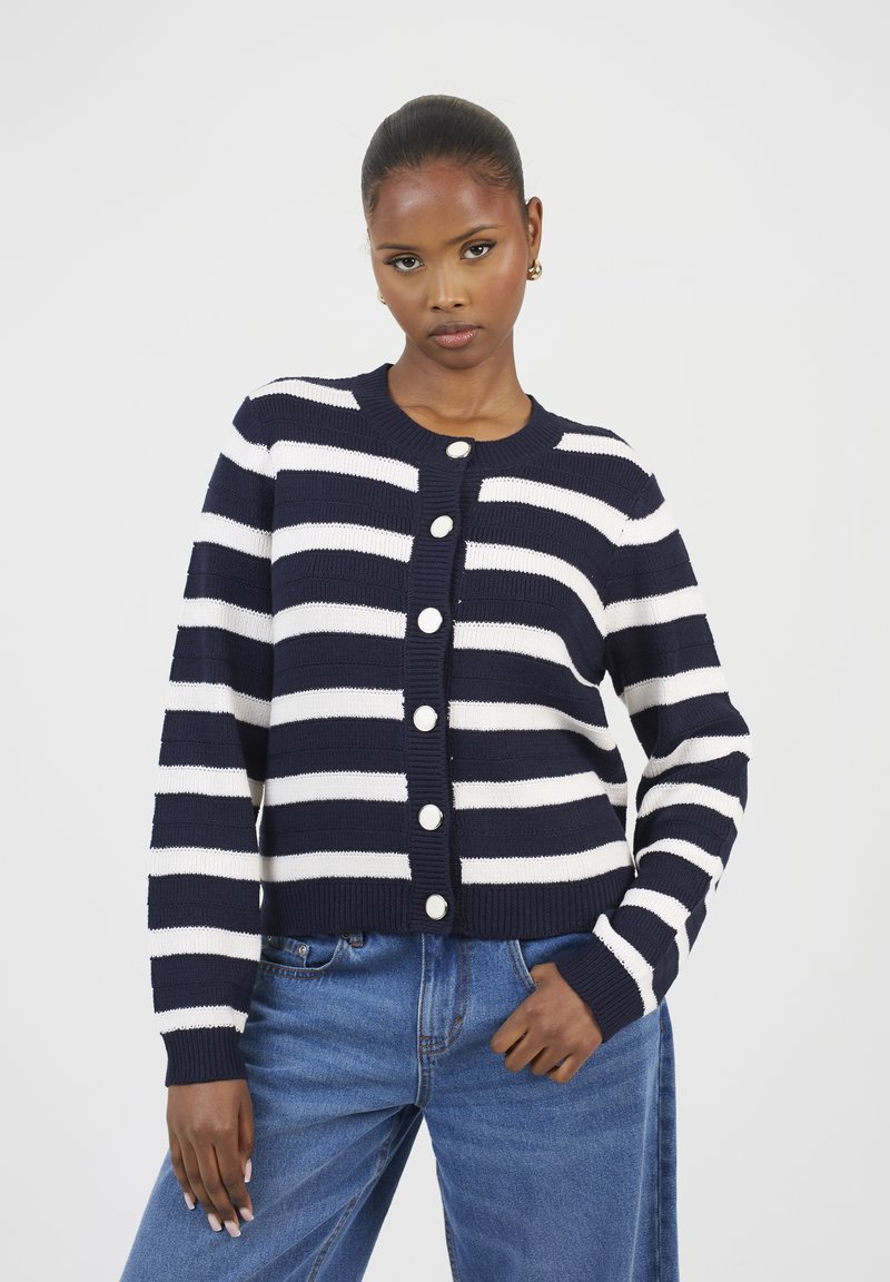 Cardigan rayé bleu marine et blanc en tissu tricoté, avec un col rond et une fermeture à boutons à l'avant comportant six grands boutons.