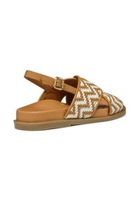 Sandalia trenzada en tonos beige y blanco con correa ajustable en el tobillo, suela de goma resistente y diseño de punta abierta. Presenta detalles de patrón geométrico.