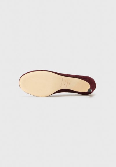 Sole di scarpa in suede bordeaux con soletta beige liscia. Presenta una punta arrotondata e una leggera texture, con un piccolo accento nero nel tallone.
