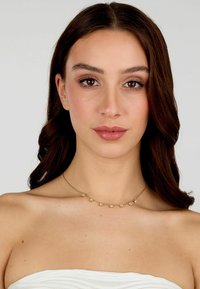 Zarte Halskette in Goldoptik mit kleinen, runden Edelsteinen, die gleichmäßig entlang der Kette verteilt sind. Einfaches Design mit glatter Oberfläche.