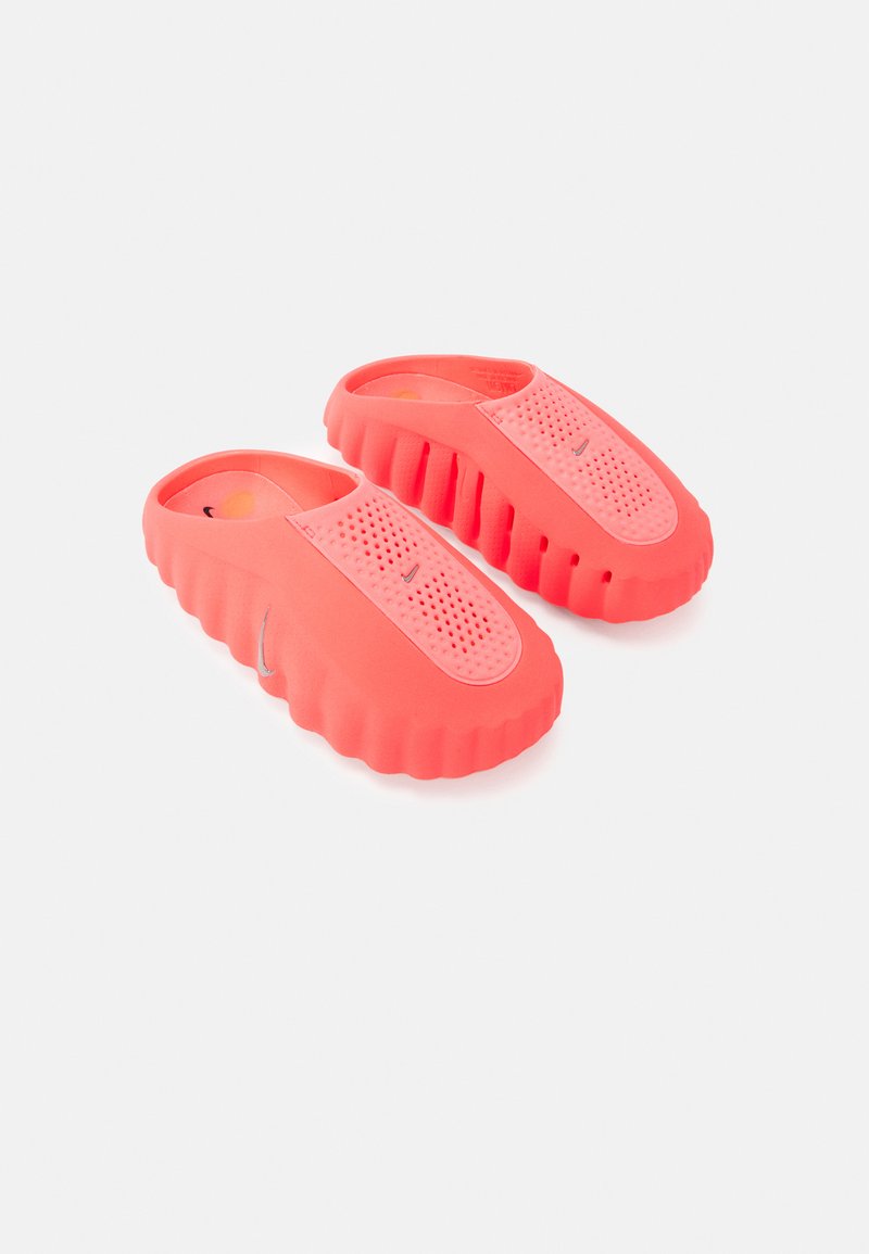 Κοραλί λαστιχένια κλογκς με υφή στην επάνω επιφάνεια, μεγάλες ανοίγματα και ραβδωτή σόλα. Διαθέτουν οπές για αναπνοή και κομψό σχέδιο.