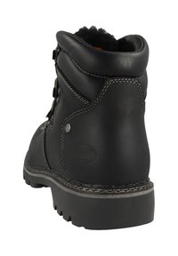 Mustat nahkasaappaat nilkkamittaisina, jossa on tikkausdetalji, metalliosat ja teksturoitu pohja. Pehmeä vuori näkyy osittain yläreunassa.