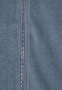 Tessuto in pile blu caratterizzato da una zip centrale con un tirante arrotondato, una consistenza liscia e sottili variazioni di colore su tutta la superficie.