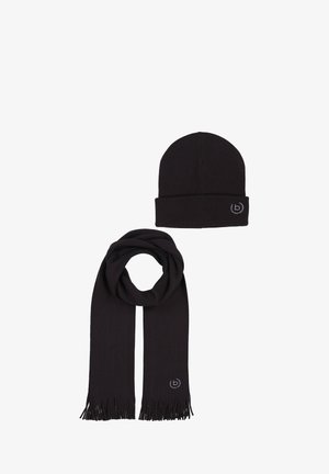 Musta kootud müts, millel on üles rullitud äär ja sobiv sall, mõlemal narmastega otsad ja väike logo. Pehme tekstuur, minimalistlik disain.