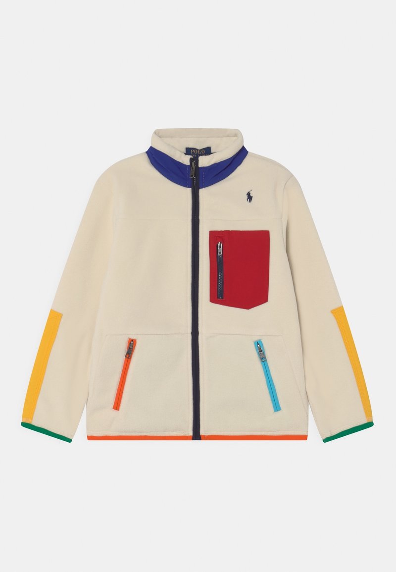 Kurtka polarowa w kolorze kremowym z zamkiem błyskawicznym, niebieskim kołnierzem, kolorowymi akcentami na rękawach, czerwoną kieszenią na piersi oraz wieloma kieszeniami na zamek.