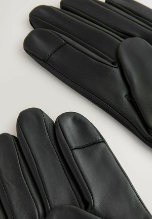 Svarta läderhandskar med en slät yta, rak sömnad och en klassisk design med rundade fingertoppar, visade sida vid sida.