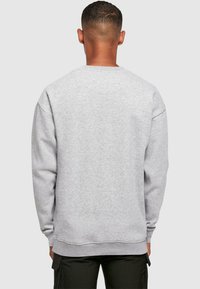 Gray sweatshirt with a crew neck, ribbed cuffs, and waistband. Features a textured fabric and relaxed fit. Plain back view.