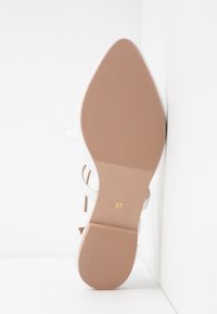 Semelle d'une sandale blanche à talons hauts à lanières, avec un bout pointu et la taille 37 imprimée en or.
