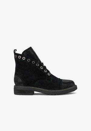 Bottine en suède noir avec des accents texturés et des détails cloutés. Elle présente un design à lacets, un bout rond et une semelle en caoutchouc robuste.