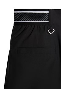 Black shorts with a contrasting striped elastic waistband, featuring a small metal loop and a back pocket. Smooth texture and minimalist design.