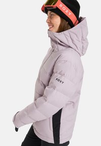 Light purple puffer jacket with a high collar, zippered front, and side pockets. Features a black side panel and "ROXY" logo on the sleeve.