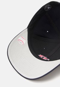 Casquette de baseball noire avec une visière grise, ornée d'un autocollant graphique de baseball et d'un logo brodé, avec des trous de ventilation disposés uniformément.