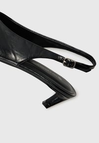 Must mustrasteltud nahk slingback kõrge kontsaga king, millel on kitsas konts, reguleeritav pandla rihm ja sile tekstuur. Lihtne ja elegantne disain.