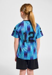 Blå och lila randig tröja med nummer 12 på ryggen, svart kant och korta ärmar, kombinerad med svarta shorts. Mjukt tyg.