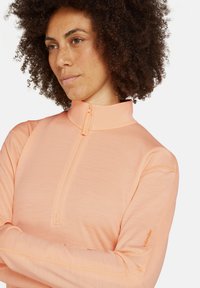 Ljust rosa kvartdrag pullover i mjukt material, med hög krage, figursydd design och subtila sömnadsdetaljer.
