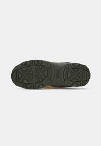 Green rubber outsole with textured tread pattern, featuring a beige and black transition. Sturdy and designed for traction on various surfaces.