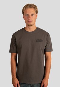 Camiseta de algodón gris con cuello redondo, mangas cortas y un sutil logo de "WRONG FRIENDS" en el lado izquierdo del pecho. Textura suave.