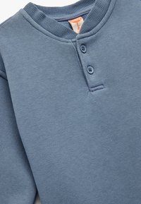 Niebieski bawełniany sweter z prążkowanym okrągłym dekoltem, zapięciem na trzy guziki i gładką fakturą; lekkotkaninowy materiał i prosty design.
