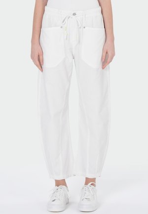 Witte losse broek met trekkoord in de taille en voorzakken, gedragen met witte sneakers, getoond van taille tot voeten op een persoon.