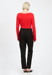 Rode lange mouwen top met een wijde halslijn, gecombineerd met zwarte op maat gemaakte broeken. De outfit heeft gladde texturen en een aansluitend design.