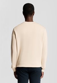 Beige sweatshirt met lange mouwen van zachte stof, voorzien van een ronde hals, geribbelde manchetten en een rechte zoom, met een gladde textuur aan de achterkant.