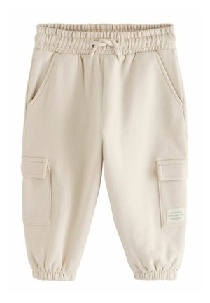 Beige cargobukser i sweatshirtstof med elastisk linning og manchetter, forlommer samt lommer med lapper på lårene og et lille trykt mærke på højre side.