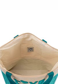 Bolsa de lona con un interior beige, acentos en teal y una etiqueta. Presenta una apertura espaciosa y un bolsillo interior.