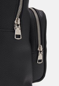 Borsa in pelle nera testurizzata con cerniere in metallo argentato dotate di tiranti brandizzati e cuciture a contrasto lungo i bordi.