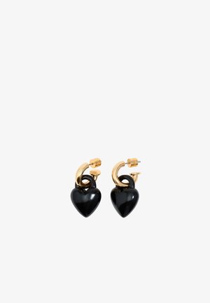 Pendientes de aro dorados con pendientes en forma de corazón negro colgando de cada aro sobre un fondo blanco.